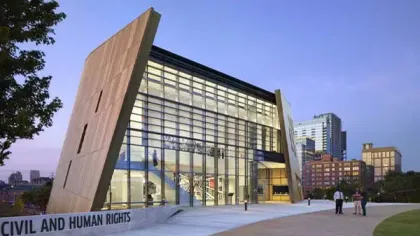 Modern Civil and Human Rights Museum with glass facade and unique angled walls in urban setting at dusk.