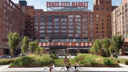 Ponce City Market brick building with large sign and people riding bicycles in front on a sunny day