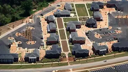 Aerial view of a modern residential complex with multiple buildings, roads, and green spaces.