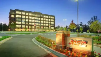 Modern office building lit up at dusk with MSC sign and landscaped surroundings in a business park.