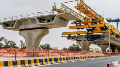 Concrete bridge under construction with large yellow crane and segmented beams over highway road.