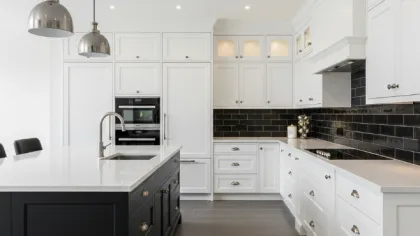Modern kitchen with white cabinetry, black subway tile backsplash, large island with sink, and stainless pendant lights