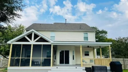 Two-story house with screened porch, covered patio, and a pool covered with a blue tarp in the backyard.