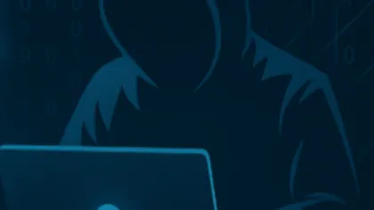 Dark hooded figure working on a laptop with binary code and circuit patterns in the background.