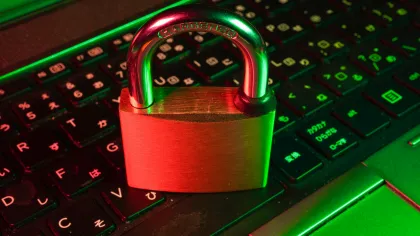 Brass padlock on a backlit laptop keyboard symbolizing cybersecurity and data protection