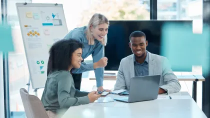 Diverse business team collaborating on a project with laptop and documents in a bright modern office.