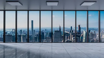 Empty modern office with floor-to-ceiling windows overlooking a city skyline on a clear day