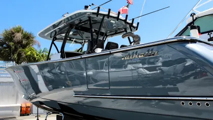 Sleek gray Valhalla powerboat docked under clear blue sky with flags and palm trees nearby