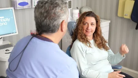 Dentist discussing treatment options with smiling female patient in dental clinic chair.