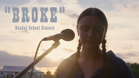 Young woman with braided hair standing by microphone at sunset with text 'Broke Sunday School Sinners'