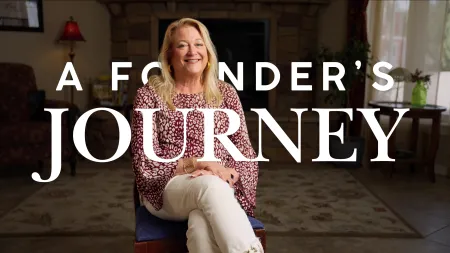 Smiling woman sitting in cozy living room with A Founder's Journey text overlay