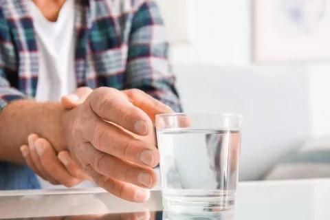 a close-up of hands holding a glass of water