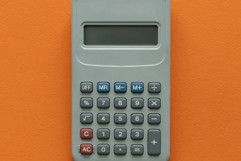 Gray calculator with blue and red buttons on an orange textured background, centered in the frame.