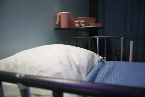 hospice care: A hospital bed with a white pillow and pastel-colored medical supplies nearby, conveying a calm healthcare setting