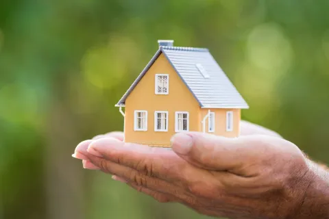 a hand holding a small house