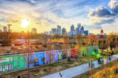 Sunset over Atlanta skyline with colorful murals, walking path, and autumn trees in Ponce City Market area.