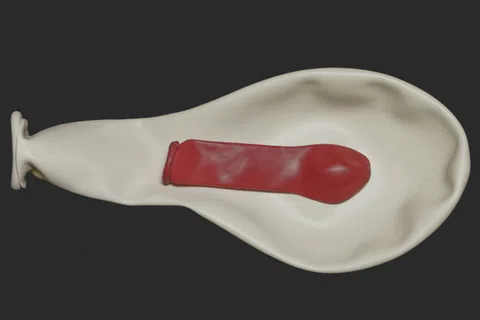 White balloon twisted to resemble an ear with a red balloon inside shaped like a smaller ear canal.