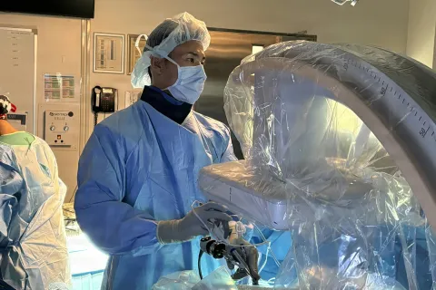 Surgeon in protective gear operating advanced medical imaging equipment in a hospital surgical room.