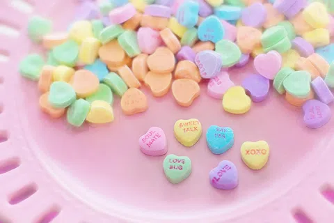 Colorful heart-shaped candy with love messages on a pink plate, perfect for Valentine's Day.