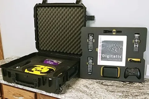 Black hard case with foam padding holding a digital kit including remotes, controllers, and a touchscreen device