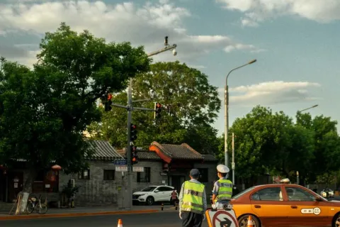 Traffic officers direct a no right turn zone with orange cones and an orange taxi on a city street under a cloudy sky.