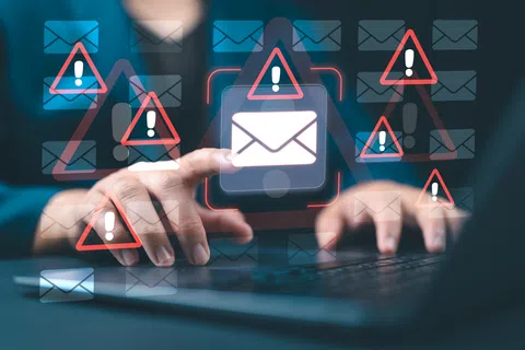 Person interacting with laptop displaying email icons and warning signs indicating email security threats.