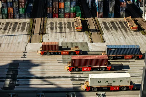 Autonomous container transport vehicles moving cargo containers at a shipping terminal emphasizing the importance of cyber security in supply chain logistics.
