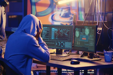 a man sitting at a desk with a computer and a monitor