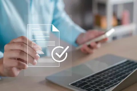 a person holding a pen and a laptop