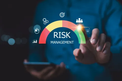 Human hand interacting with digital risk management gauge showing low to high risk indicators.