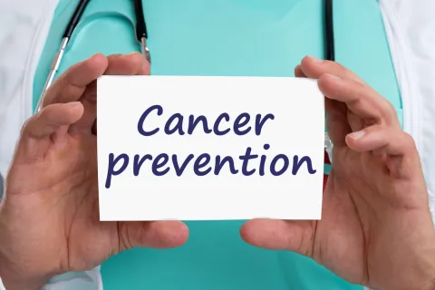 Person holding a sign that says National Cancer Prevention Month; to raise awareness about cancer prevention efforts.