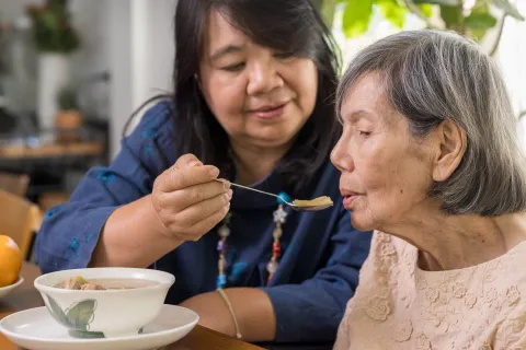 Woman feeding her elderly mother