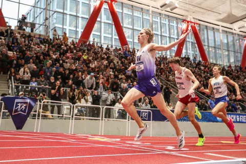 a group of people running on a track with a crowd watching