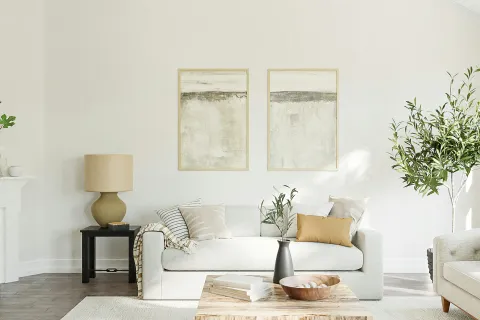 a living room with a white couch and a white wall with art on it