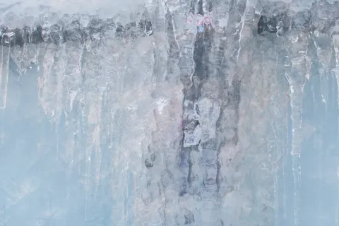 Frozen icicles hanging with blurred winter background creating a cold icy texture and pattern