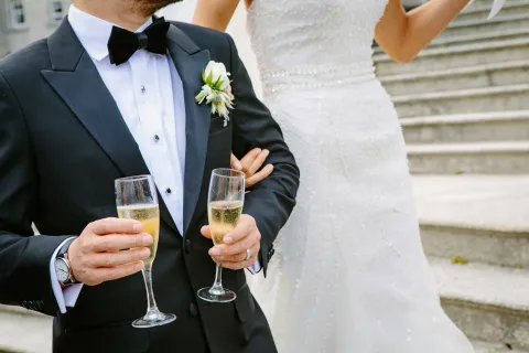 a person in a tuxedo holding a glass of champagne