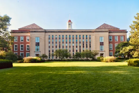 a large brick building with a grassy field