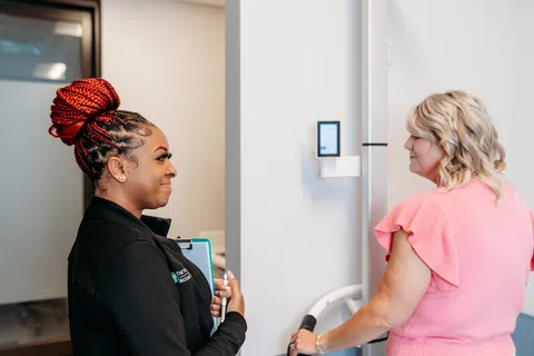 A Beltline Health staff member talking with a patient beside a body composition analyzer during a weight loss visit