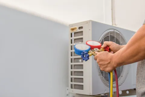 Technician checking refrigerant levels of air conditioning unit