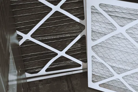 Close-up of clean and dirty air conditioner filters illustrating HVAC maintenance and air quality.