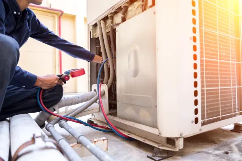 HVAC technician inspecting an outdoor air conditioning unit to diagnose performance issues.