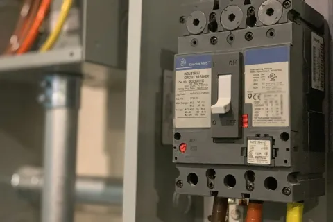 Close-up of an industrial circuit breaker with colored wiring in an electrical panel.