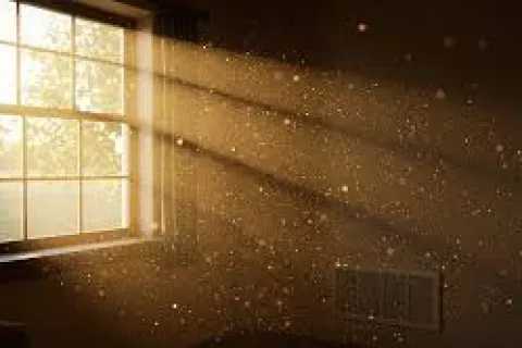 Sunlight streaming through a window illuminating dust particles in a dimly lit room.