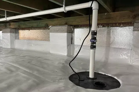 Clean, bright crawl space with white vapor barrier and installed sump pump system for moisture control.