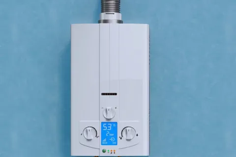 White tankless water heater with temperature and pressure controls mounted on blue wall with metal exhaust pipe.