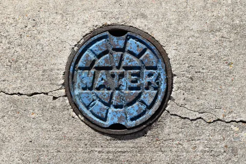 Blue water utility cover on cracked concrete pavement indicating underground water access point.