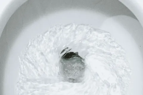 Clear water swirling rapidly inside a white toilet bowl during flushing action