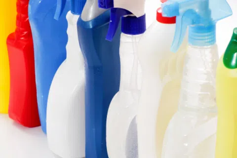 Various colorful spray bottles and cleaning product containers arranged in a row on a white surface.