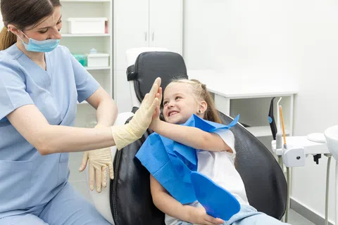 Child patient giving a high-five to a smiling female dentist in a dental clinic