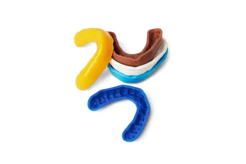 Various colored dental impression trays and molds used for taking teeth impressions on white background